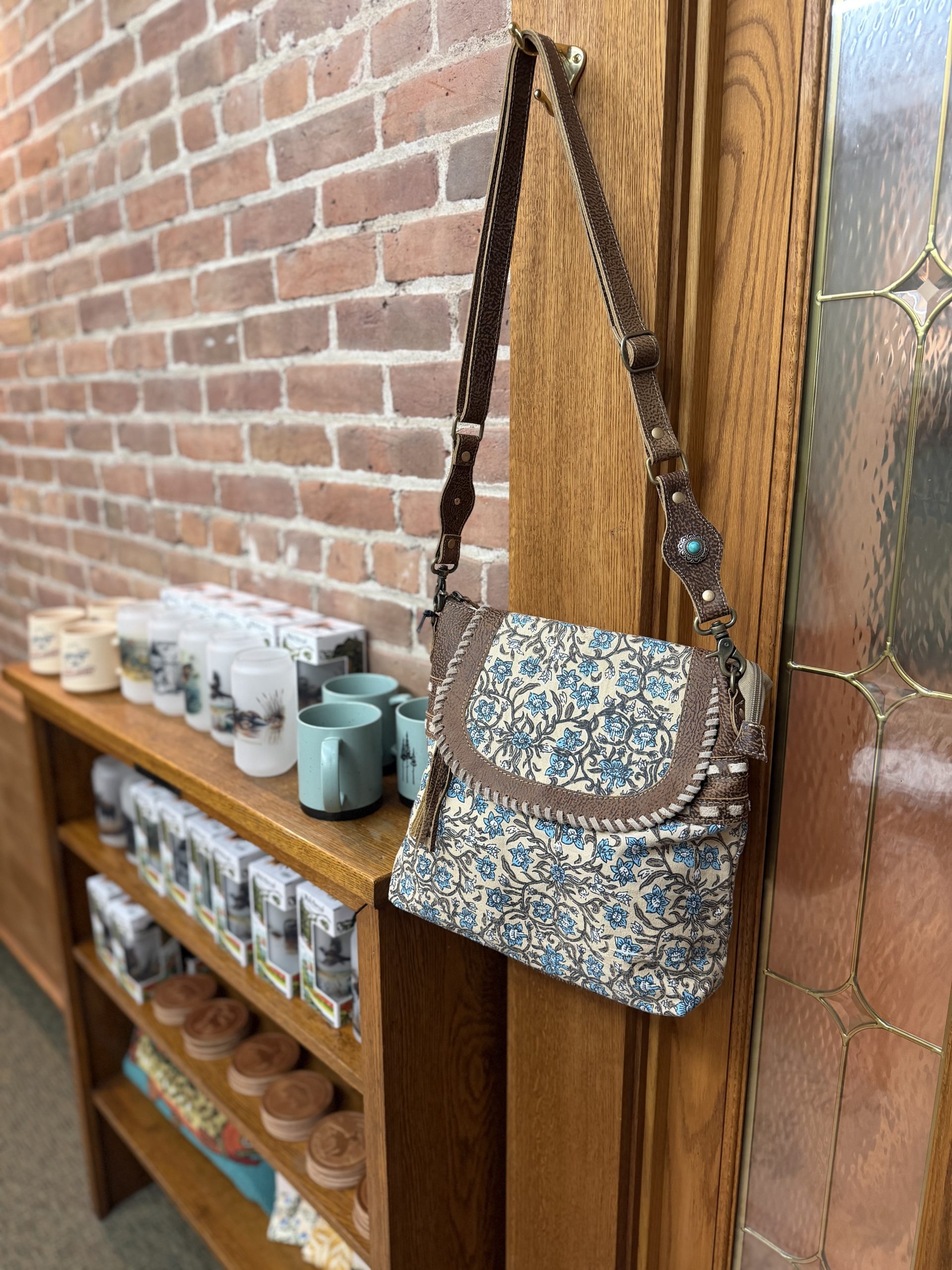 Blue block-print crossbody bag with brown leather whipstitch trim and turquoise concho strap