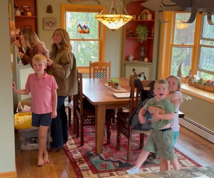 A busy family moment at home: a mom and her three young children in the dining room